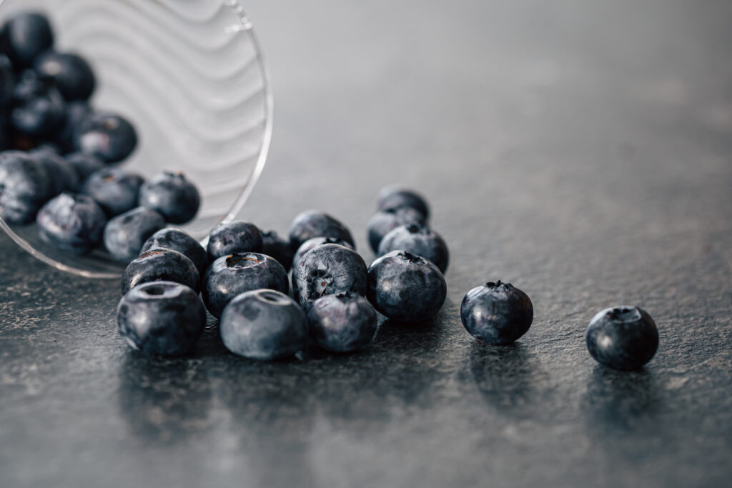 macro photography, blueberries scattered on a dark surface.