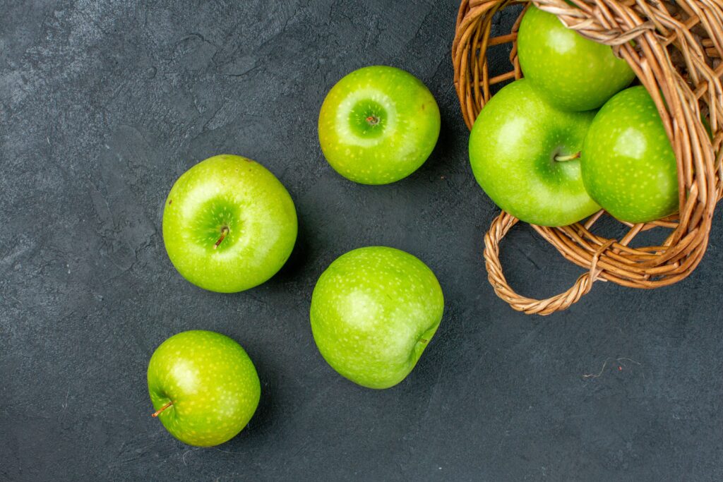 top view fresh apples scattered from wicker basket dark surface (2)