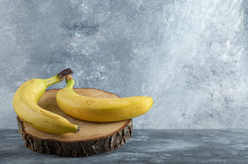 two ripe bananas wooden board grey background (2)